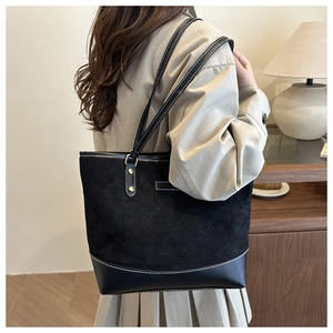 Detail of black tote bag featuring diamond quilted stitching and mixed leather textures