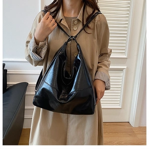 Detalle del bolso tote de cuero negro brillante combinado con una gabardina caqui