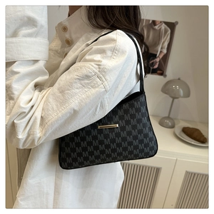 Close-up of minimalist black bucket bag with gray M-pattern and gold metal bar