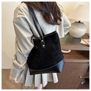 Detail of black suede tote bag with contrast white stitching and gold metal rivets