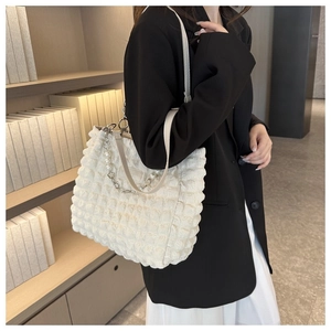 Detail van de witte tote tas met bubbelstructuur en decoratieve parel- en metalen ketting