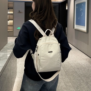Rückansicht eines cremeweißen großen Mode-Rucksacks, getragen von einer Person im Flur