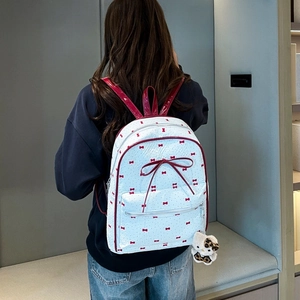 Rear view of a white bow-knot backpack with red polka dot pattern on a female model