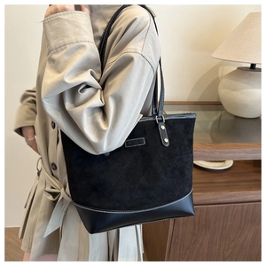 Detail of black tote bag with suede texture, leather patchwork and gold metal hardware