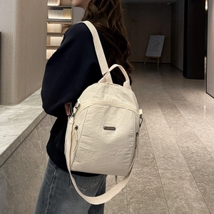 Detailansicht der Seitenansicht eines beigen Nylonrucksacks für Reisen und Pendeln am Modell