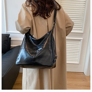 Detail of a black oily leather Hobo bag with adjustable strap on a shoulder