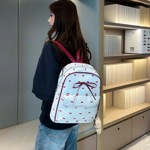 White backpack with red bow patterns shown from side view on a model in a library