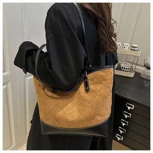 Close-up of brown suede tote bag with quilted diamond pattern and black leather handles