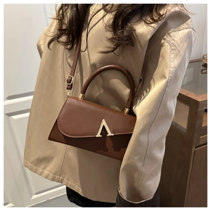 Close-up of brown leather evening bag with golden A-shaped metal buckle and top handle