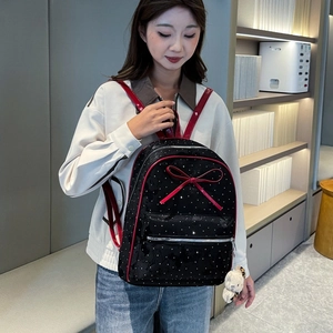 Close-up of a stylish black polka dot backpack with a red bow and a cute teddy bear charm