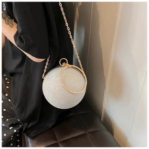 Detailed macro view of the silver glitter sphere bag with gold metal ring handle and chain