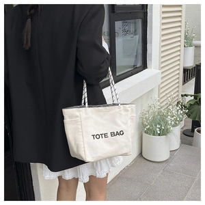 Street style shot of cream canvas tote bag with black rope handles and TOTE BAG print