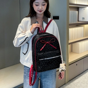 Detail of black polka dot backpack with a red bow and plush kitten charm on side