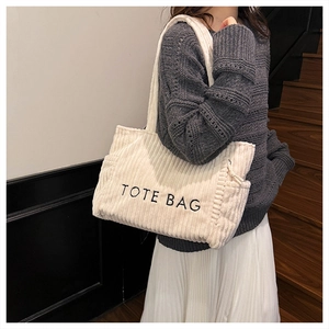 Detail der cremeweißen Cord-Tragetasche mit TOTE BAG Stickerei und weicher Textur