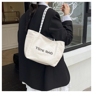 Close-up of cream canvas tote bag showing textured fabric and side pocket detail