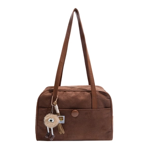 Retro brown suede underarm bag with large front pocket and plush ball charm in main view