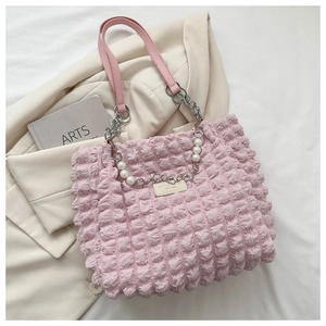 Detail van roze handtas met bubbelstructuur en parelketting met hartje en leren greep