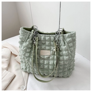 Detail van mintgroene puff-tote-bag met parelketting en gewatteerde textuur van de stof