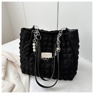 Detail van zwarte gewatteerde shopper met bubbeltextuur, zilveren ketting en parel