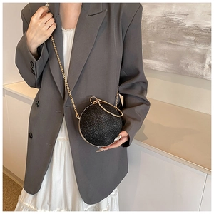 Chic black sequin spherical evening bag with golden round handle and chain strap on model