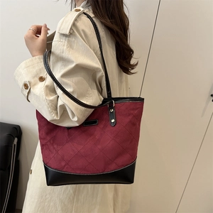Chic burgundy quilted tote bag with black trim, styled on model for daily commuting