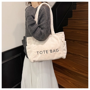 Detail of off-white corduroy tote bag with black TOTE BAG embroidery and side pockets