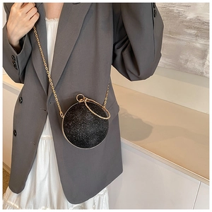 Detail of glitter spherical evening bag with gold ring handle and chain on model