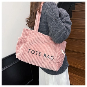 Close-up of pink corduroy tote bag with TOTE BAG print and side pocket detail