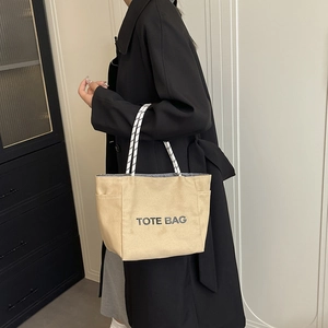 Large beige canvas tote bag with black letter print and woven shoulder straps