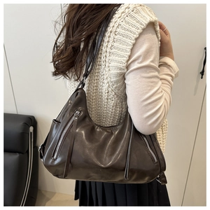 Detailed side view of dark brown retro crossbody bag featuring silver zippers and soft leather