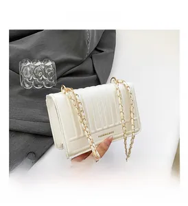 Detail of white quilted crossbody bag with golden chain strap and fashion lettering