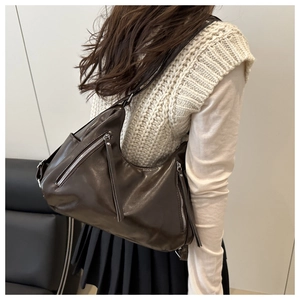 Detail of a dark brown vintage hobo shoulder bag with silver zippers and long tassels