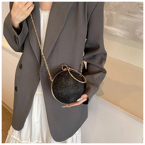 Detail of a sparkling black spherical evening bag with a gold rhinestone ring handle