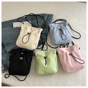 Platte weergave van mini nylon crossbodytassen met trekkoord in vijf kleuren op textuur