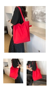 Close-up of a large red nylon tote bag with drawstring closure and wide shoulder strap
