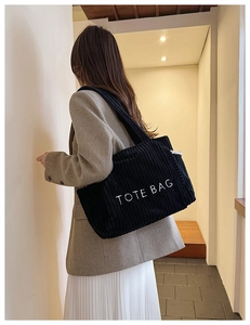 Détail montrant la texture du velours côtelé noir et la broderie blanche TOTE BAG du sac