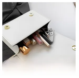 Detail showing the internal storage of the white chain bag with cosmetic items