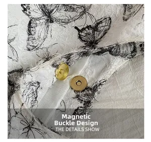 Dettaglio della chiusura magnetica dorata sulla borsa bianca con ricamo a farfalla