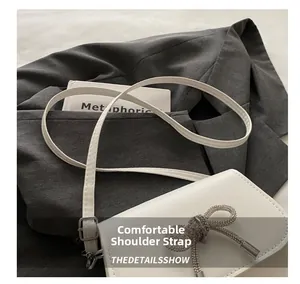 Detail of white leather saddle bag with a luxury rhinestone bow and adjustable strap