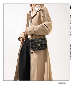 Détail du sac à bandoulière en tweed noir avec fermoir doré sur un trench-coat élégant