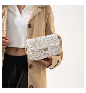 Détail de la texture d'un sac en tweed blanc avec fermoir doré et bandoulière chaîne