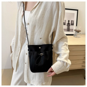 Detailopname van een minimalistische zwarte nylon crossbodytas met decoratief koord