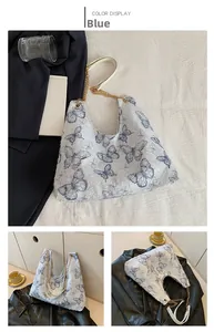 Dettaglio della borsa tote in tela con farfalle blu e tracolla in catena dorata