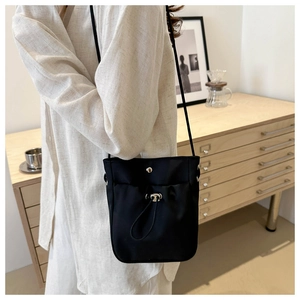Détail du sac à bandoulière minimaliste en tissu oxford noir avec boucle argentée fine