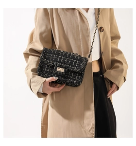 Détail d'un sac en tweed noir et blanc avec chaîne et fermoir tournant doré