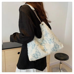 Dettaglio della borsa tote in tweed bianco con farfalle ricamate e tracolla dorata