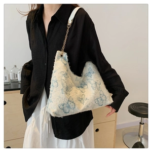 Detailed close-up of a white canvas bag with blue butterfly print and gold chain strap