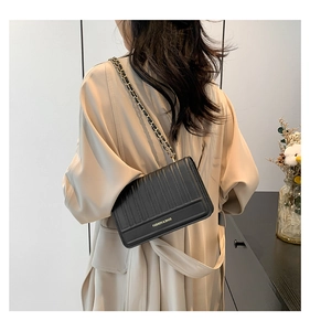 Sac à bandoulière noir matelassé avec chaîne dorée, présenté sur le dos du mannequin