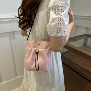 Sac bandoulière minimaliste en nylon rose avec cordon de serrage porté par un mannequin
