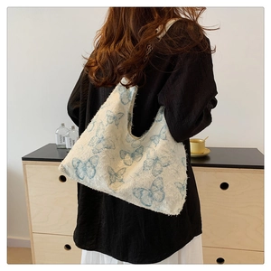 Dettaglio della borsa tote in tela bianca con stampe di farfalle blu e frange